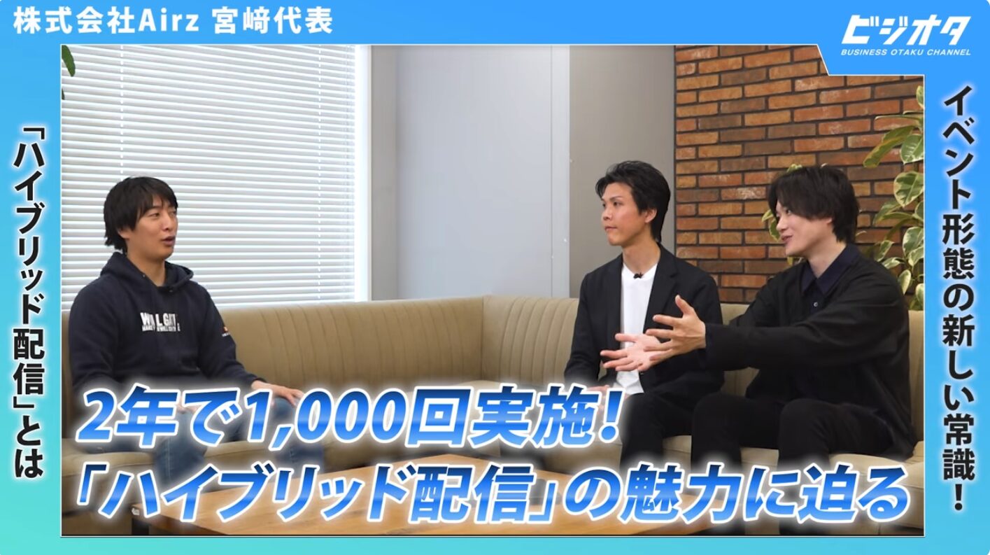 Video thumbnail: three men sit on a beige sofa in a modern office, discussing on a blue-framed channel, with Japanese title about 'hybrid delivery'.