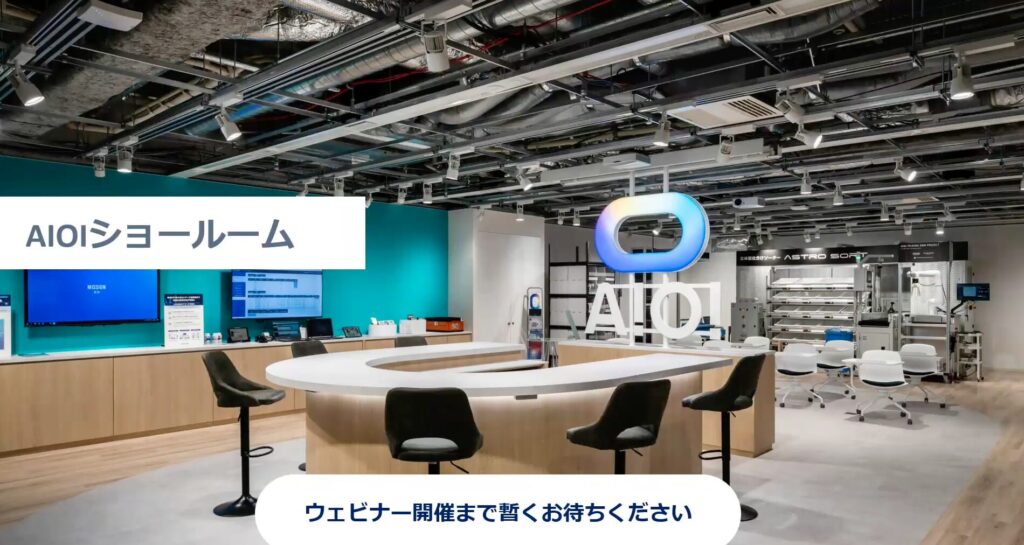 AIO showroom interior with a circular white information counter, black stools, teal wall, and a large illuminated AIO logo.